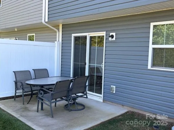 a patio with table and chairs and potted plants