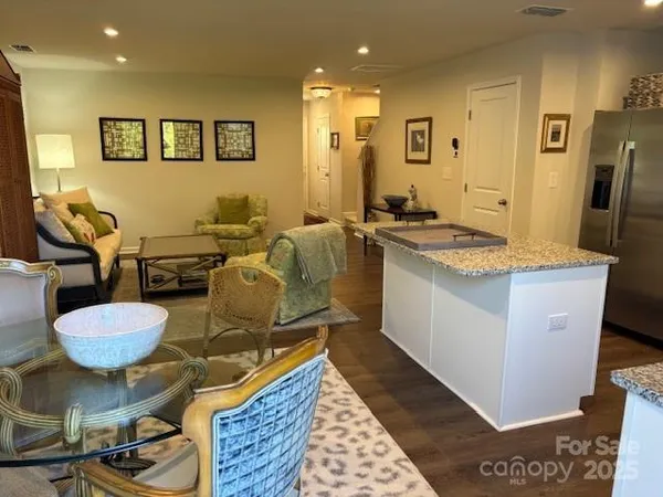 a kitchen with stainless steel appliances granite countertop a sink a stove a refrigerator a microwave oven with white cabinets and wooden floor