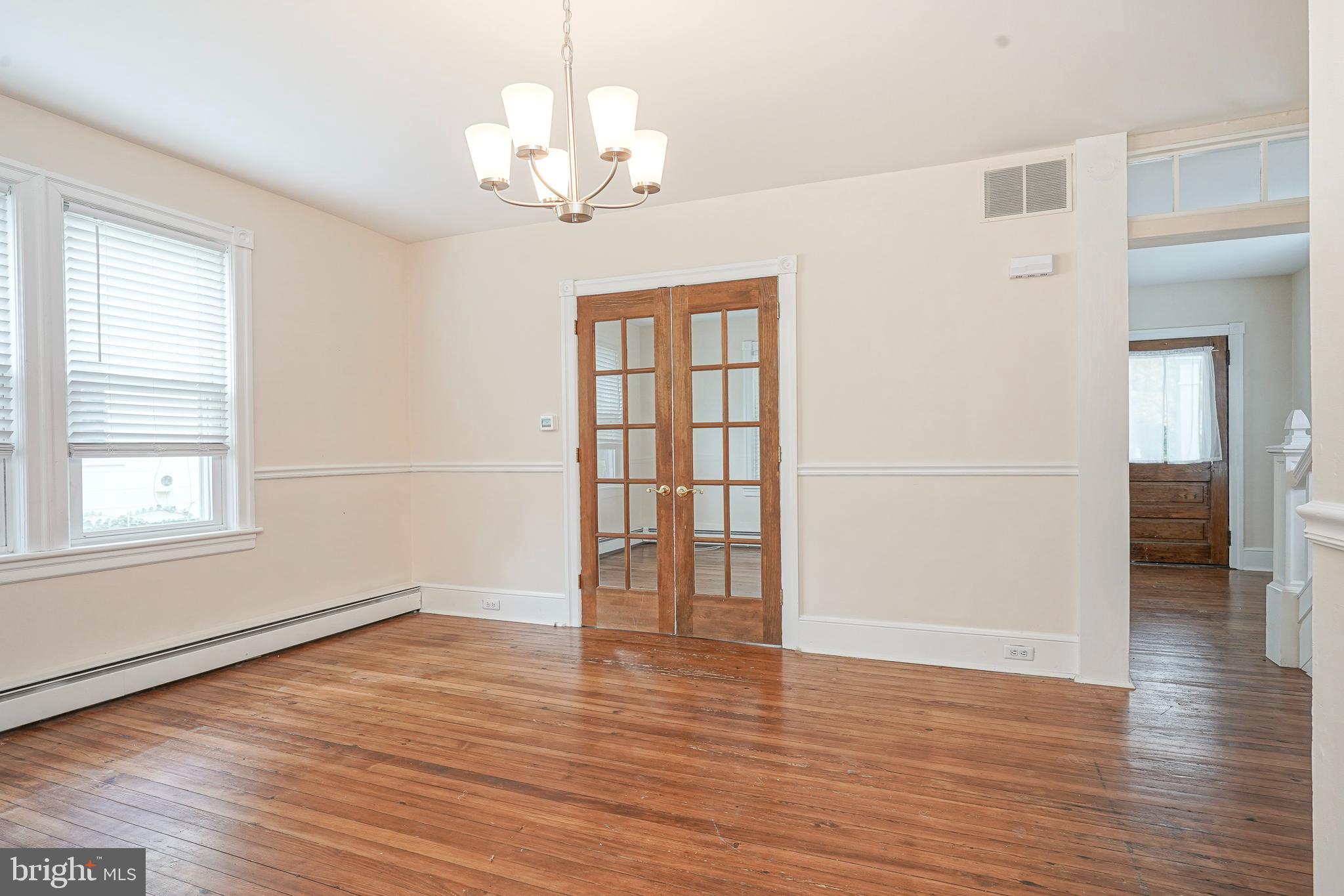 107 Colonial Avenue Haddonfield, NJ 08033 - Photo 8 of 29 an empty room with wooden floor chandelier and windows
