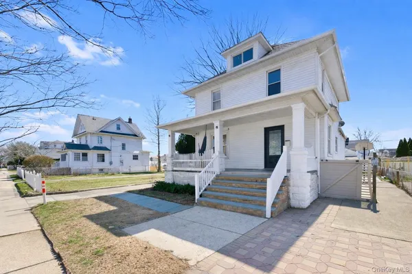 a view of a white house with a small yard and sitting area