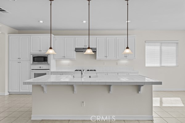 341 Caldera Street Perris, CA 92570 - Photo 21 of 53 a kitchen with stainless steel appliances granite countertop a sink a oven a stove and white cabinets