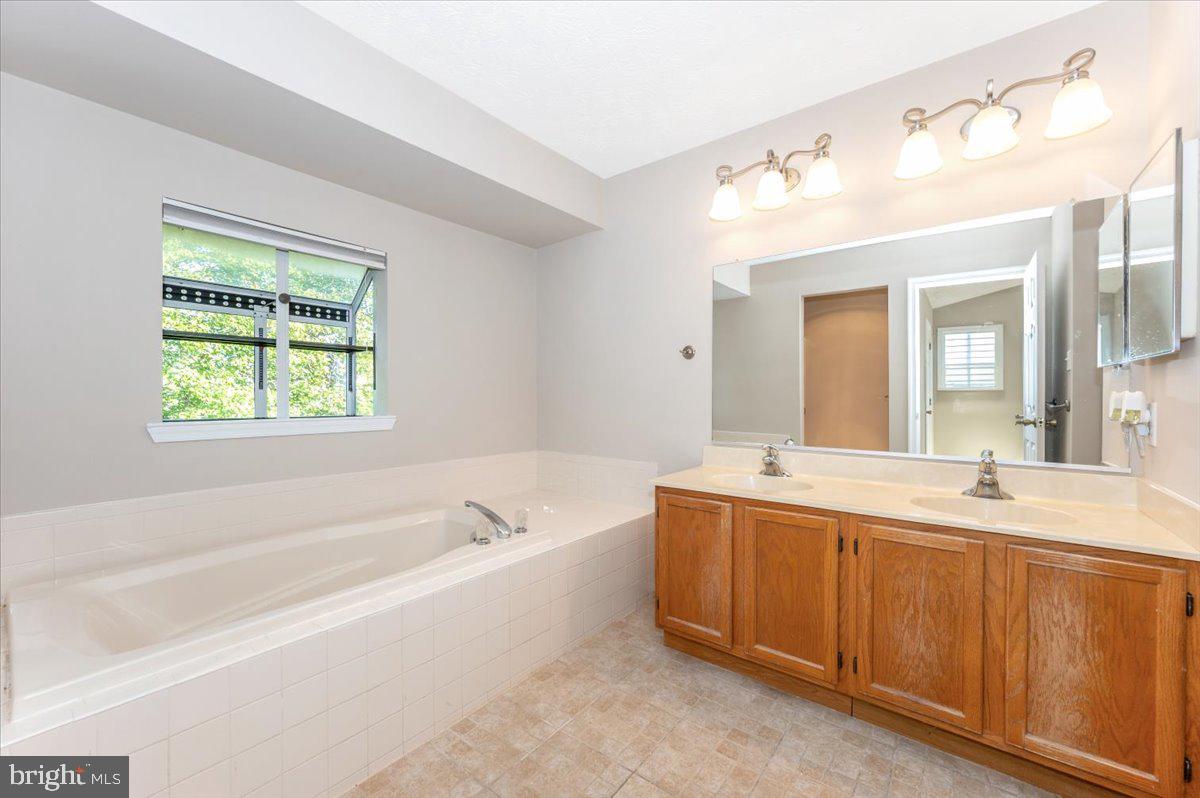 5004 Finch Court Frederick, MD 21703 - Photo 30 of 63 a spacious bathroom with a tub sink and mirror