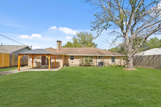 a view of a house with a big yard and large trees