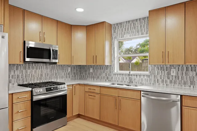 a kitchen with stainless steel appliances granite countertop a sink a stove a microwave and wooden cabinets