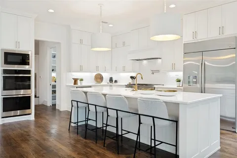 a kitchen with stainless steel appliances granite countertop a sink a stove a refrigerator and island with wooden floor