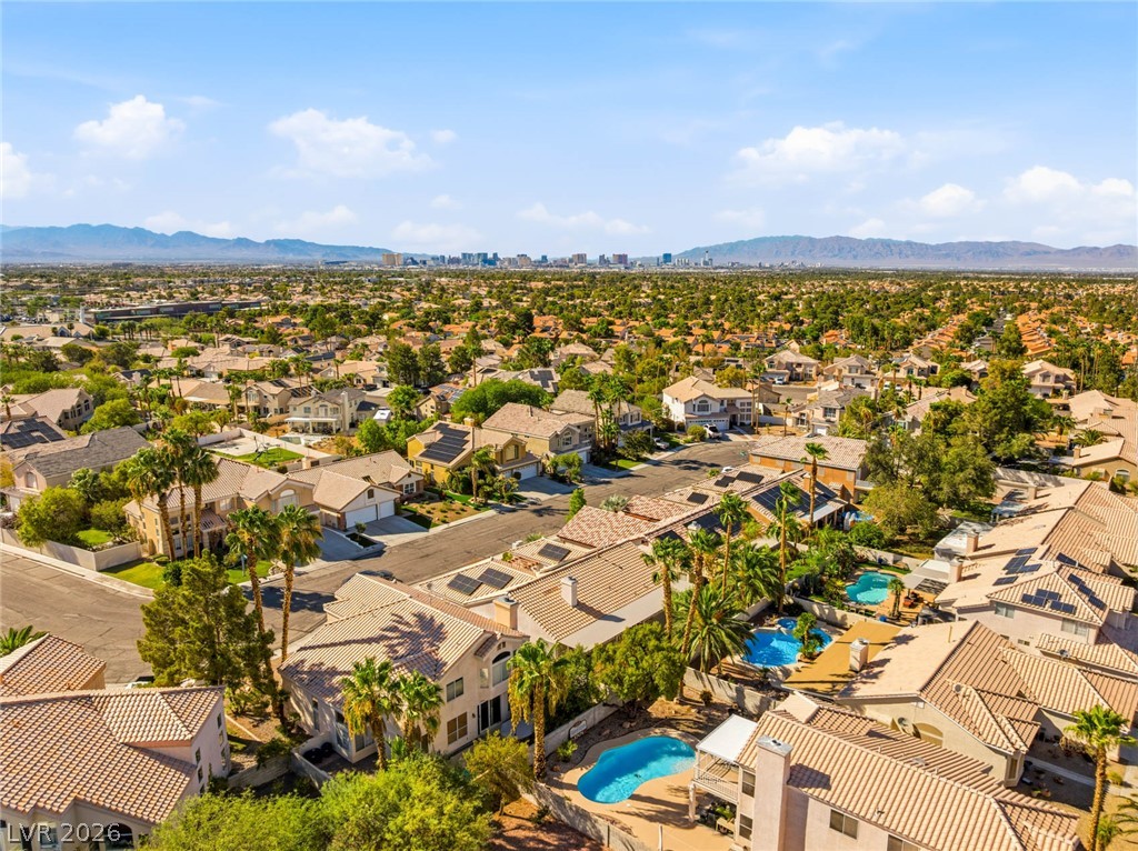 9034 Ridgepointe Way Henderson, NV 89074 - Photo 49 of 56 Sweeping mountain and skyline views overlook a vibrant neighborhood lined with palm trees.