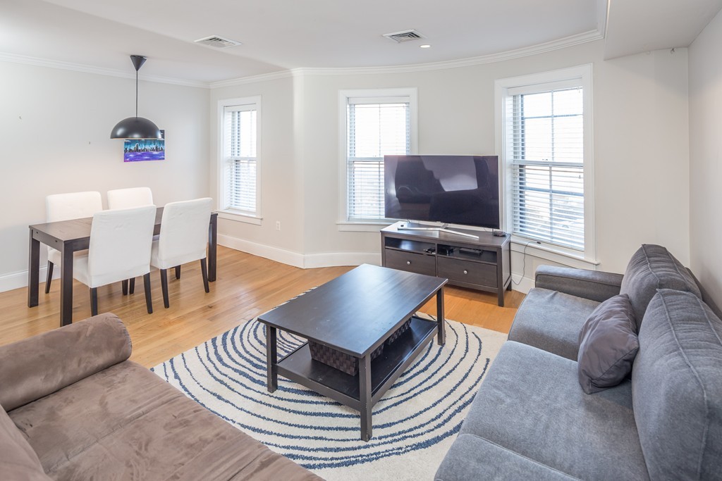 a living room with furniture a flat screen tv and a window