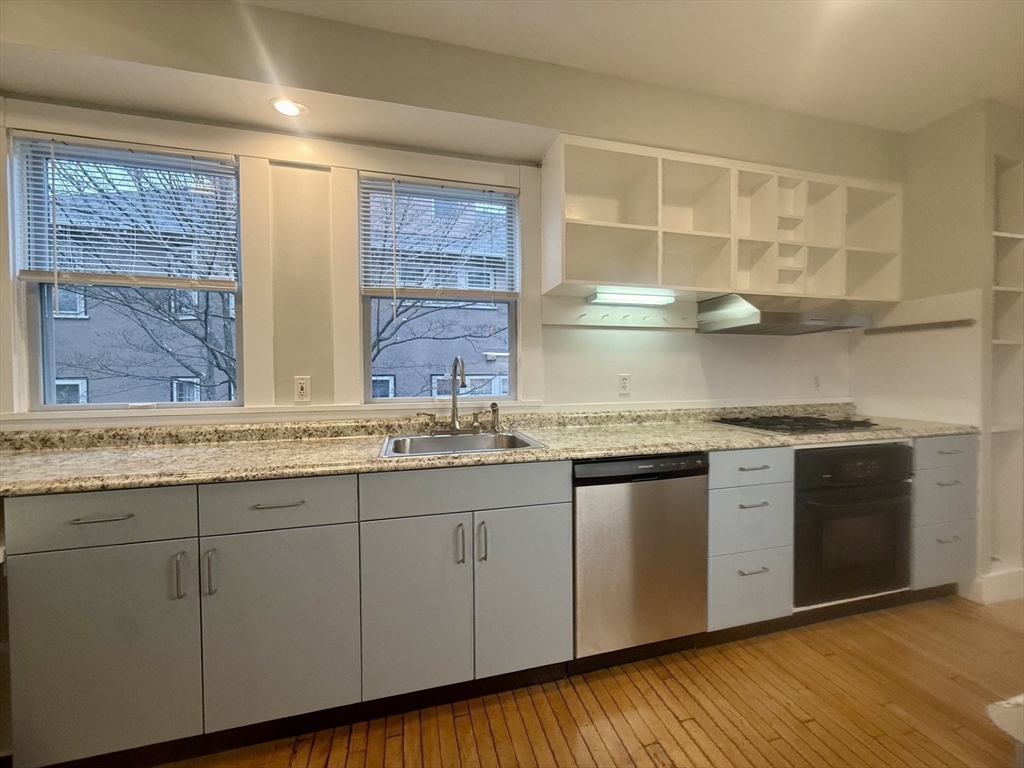 172 Maplewood Street, Unit 172 Watertown, MA 02472 - Photo 17 of 29 a kitchen with stainless steel appliances granite countertop a sink and cabinets with wooden floor