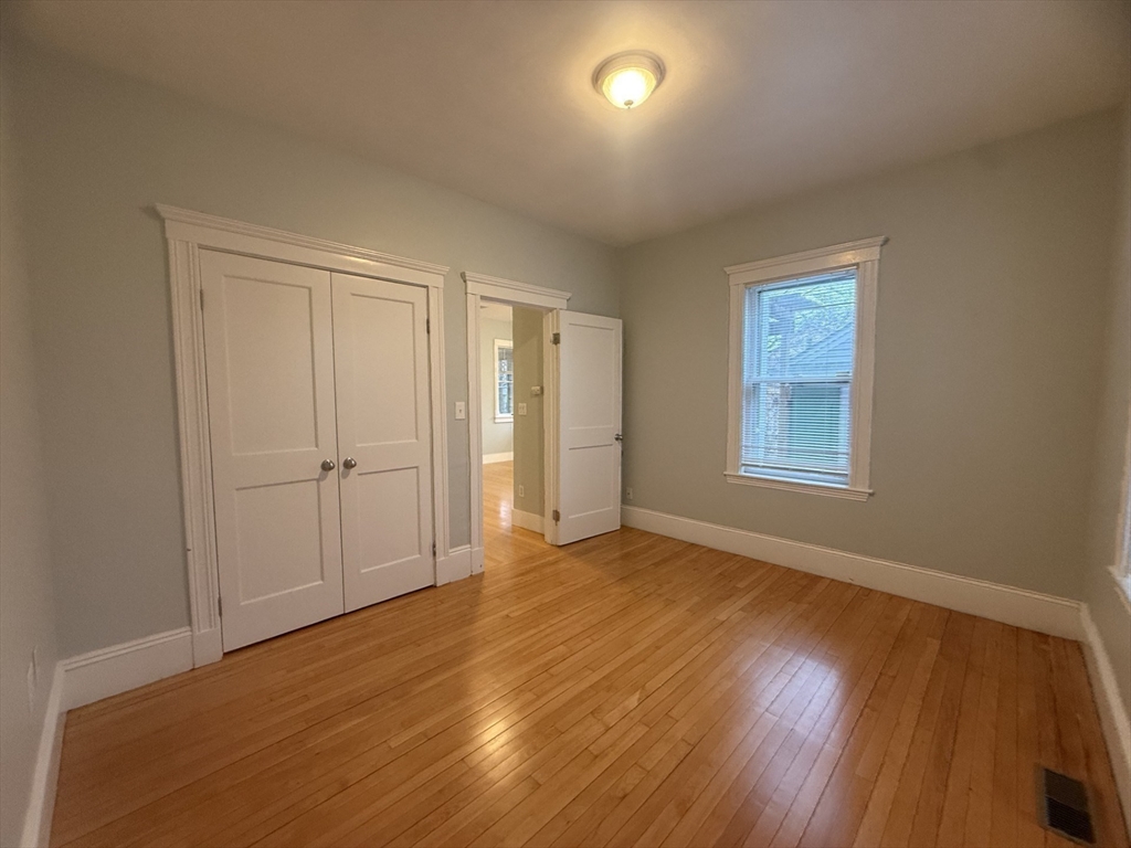 172 Maplewood Street, Unit 172 Watertown, MA 02472 - Photo 23 of 29 an empty room with wooden floor and windows