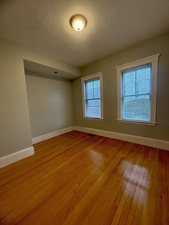 172 Maplewood Street, Unit 172 Watertown, MA 02472 - Photo 5 of 29 an empty room with wooden floor and windows