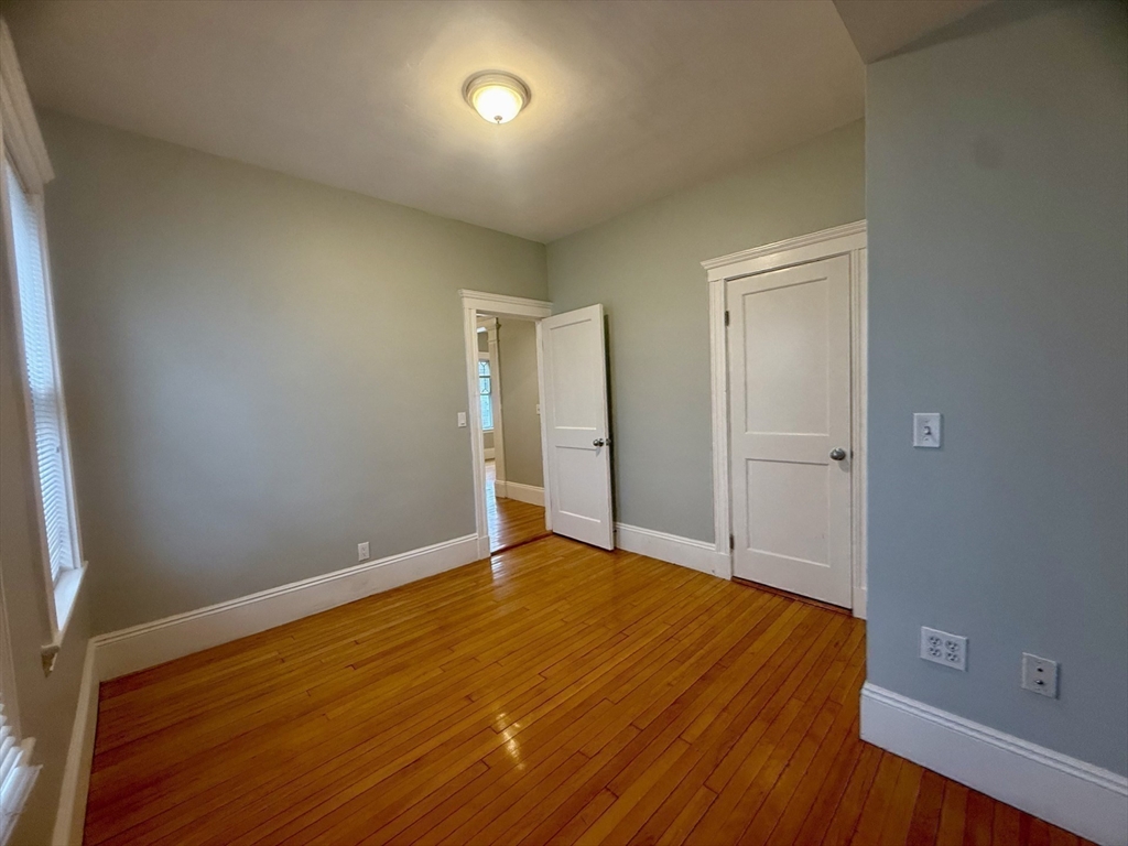 172 Maplewood Street, Unit 172 Watertown, MA 02472 - Photo 6 of 29 a view of an empty room with wooden floor and a window