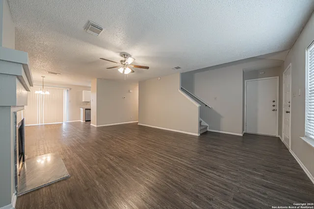 a view of an empty room with wooden floor and a ceiling fan