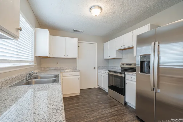 a kitchen with granite countertop white cabinets and white appliances