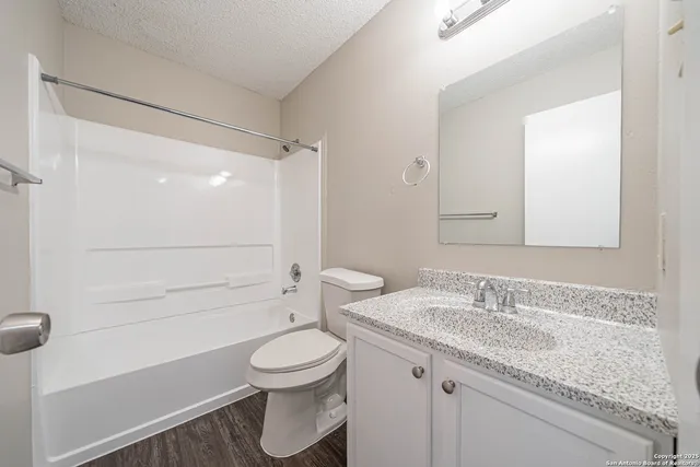 an empty room with chandelier fan and windows