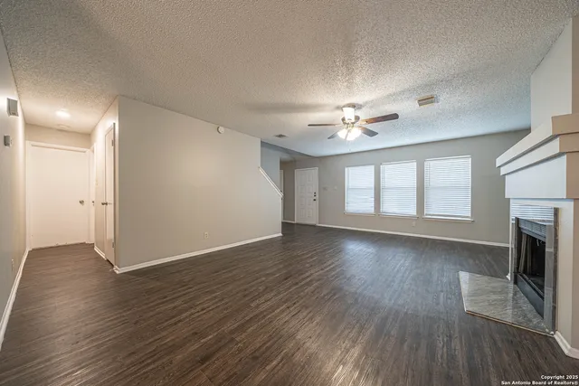 an empty room with wooden floor fireplace and windows