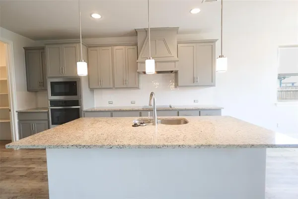 a kitchen with granite countertop a sink a center island stainless steel appliances and cabinets