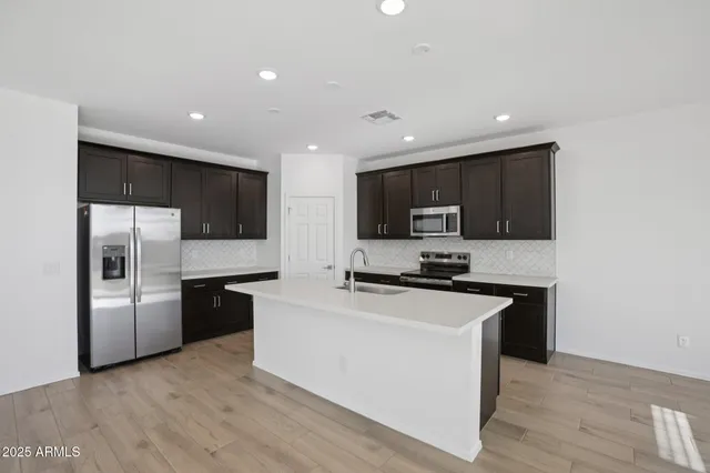 a kitchen with stainless steel appliances a stove top oven a refrigerator and a sink
