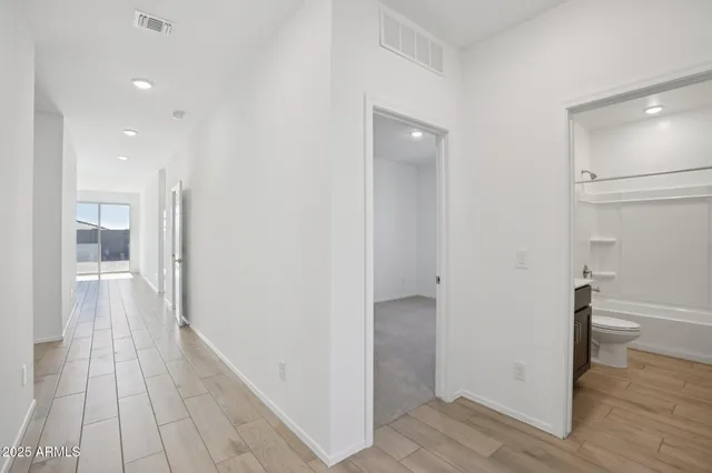 a view of a hallway with wooden floor and a bathroom