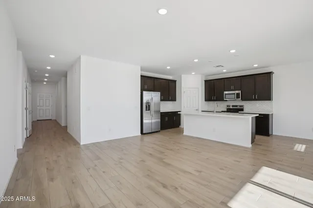 a view of kitchen with kitchen island granite countertop stainless steel appliances refrigerator oven and cabinets