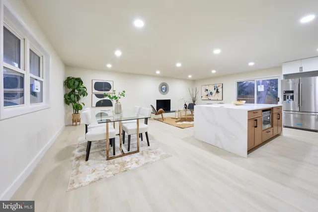 a living room with stainless steel appliances furniture a rug and a kitchen view