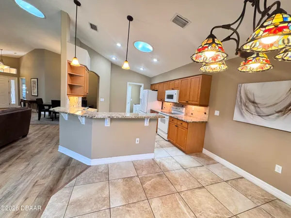 a large kitchen with stainless steel appliances granite countertop a stove cabinets and living room view