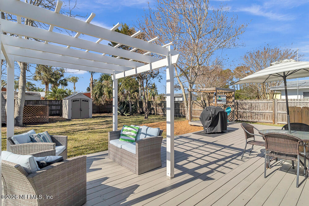 5437 3rd Street St. Augustine, FL 32080 - Photo 30 of 35 a view of a patio with couches table and chairs under an umbrella with wooden floor