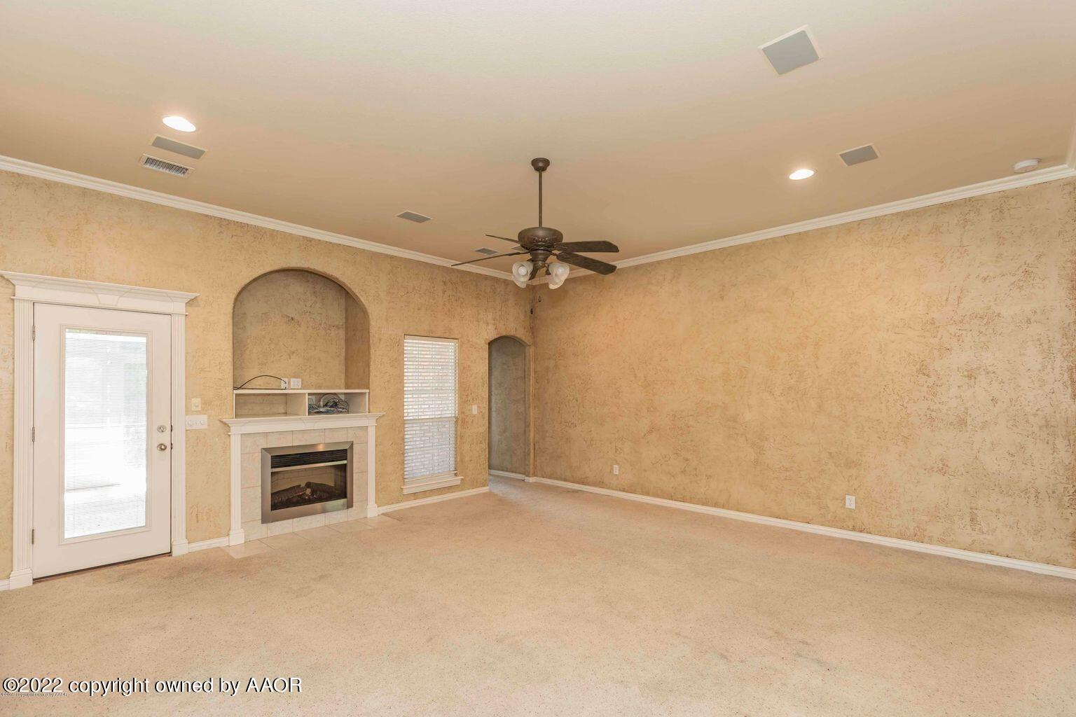 5801 South Rusk Street Amarillo, TX 79118 - Photo 2 of 27 an empty room with a fireplace and a ceiling fan