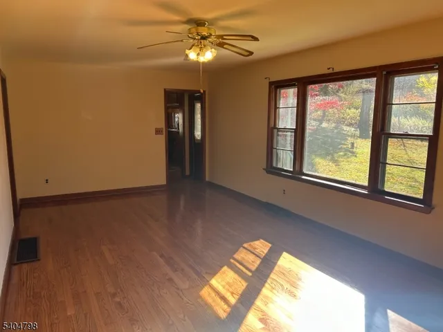 a view of an empty room with wooden floor and windows