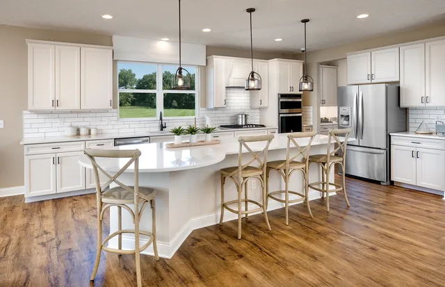 a kitchen with stainless steel appliances kitchen island granite countertop a wooden floor and white cabinets