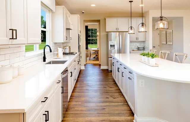 a large white kitchen with a large window and stainless steel appliances