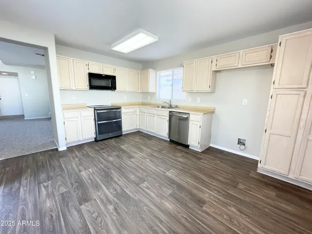 a kitchen with a sink wooden floor and stainless steel appliances
