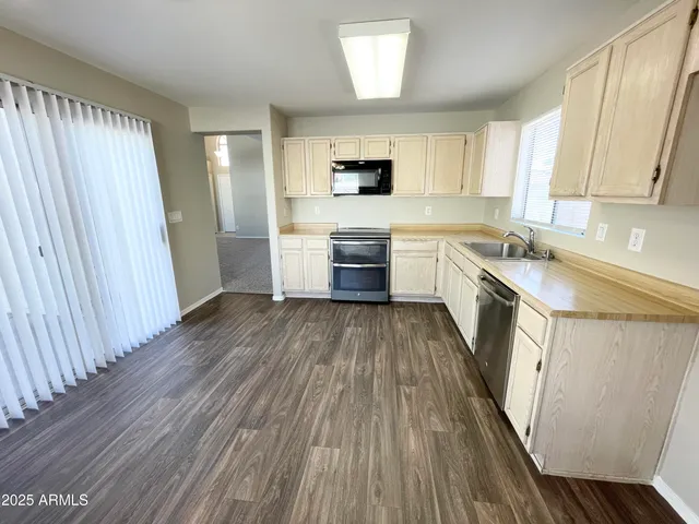 a kitchen with a sink wooden floor and stainless steel appliances
