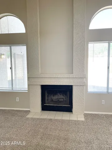 an empty room with windows and fireplace