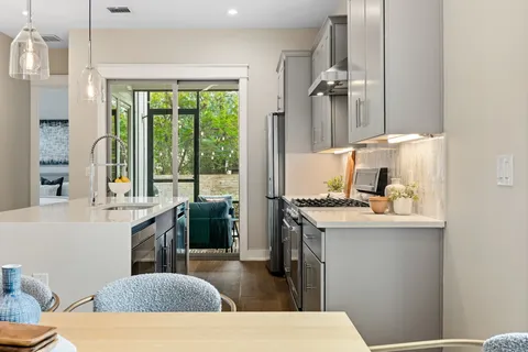 a kitchen with stainless steel appliances granite countertop a refrigerator a sink dishwasher a stove a dining table and chairs with wooden floor