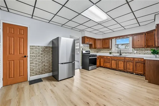 a view of kitchen with stainless steel appliances wooden floor and window