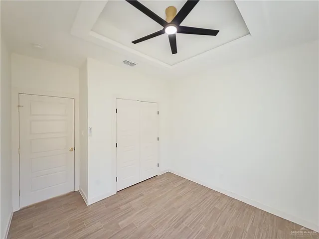 an empty room with wooden floor closet and ceiling fan