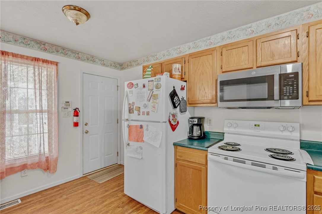 317 Kernstown Road Raeford, NC 28376 - Photo 16 of 32 a kitchen with stainless steel appliances a stove a microwave a refrigerator a cabinets and wooden floor