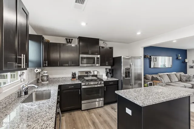 a kitchen with stainless steel appliances granite countertop a sink a stove and a refrigerator