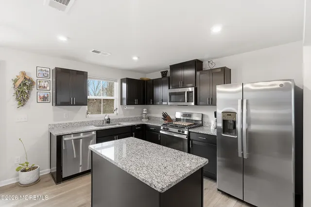 a kitchen with a refrigerator a sink a stove a microwave cabinets and wooden floor