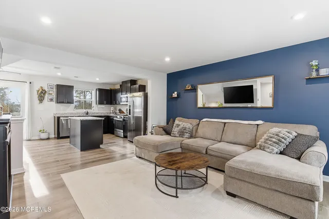 a living room with furniture kitchen view and a wooden floor