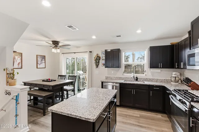 a kitchen with a stove a sink dishwasher a dining table and chairs with wooden floor