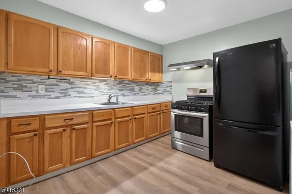 a kitchen with granite countertop stainless steel appliances a refrigerator and cabinets
