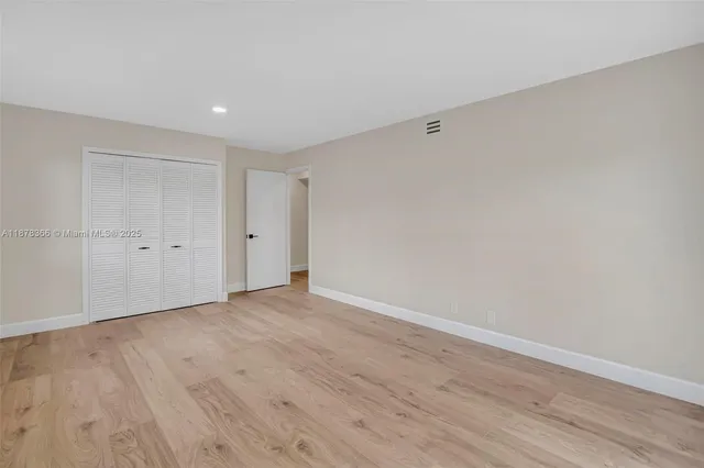 a view of an empty room with wooden floor and windows