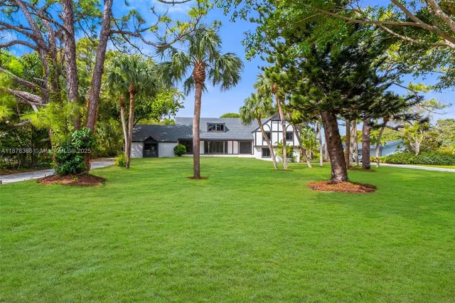 a view of a house with a big yard plants and large trees