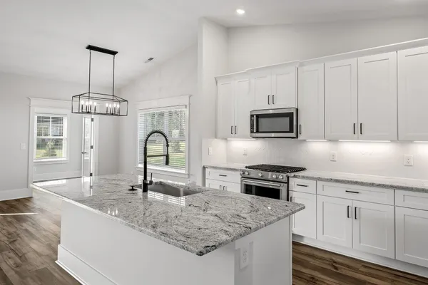 a kitchen with stainless steel appliances granite countertop a sink stove and cabinets