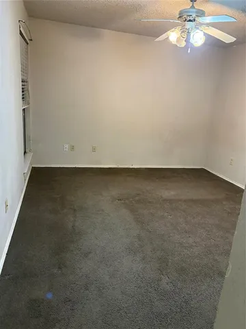 an empty room with a chandelier fan and windows