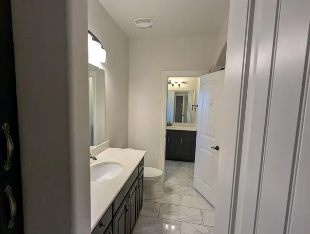 a bathroom with a sink and mirror with toilet