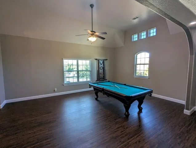 a room with pool table windows and wooden floor