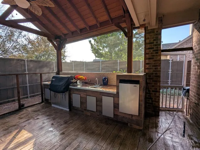 a view of a patio with table and chairs a barbeque with wooden floor and roof with a garden view