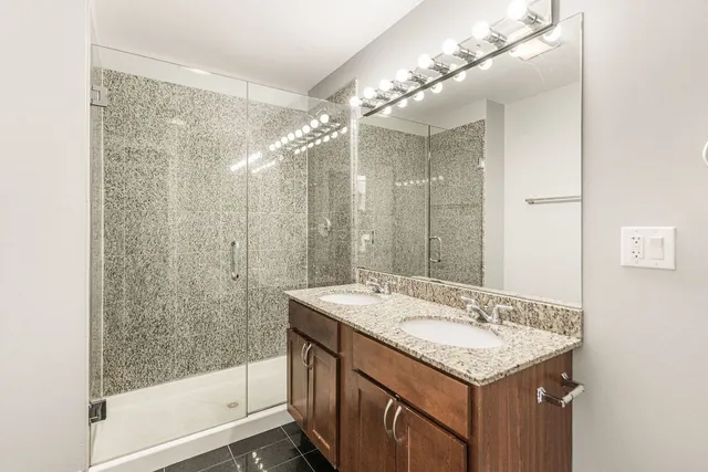 a bathroom with a granite countertop sink a mirror and a shower